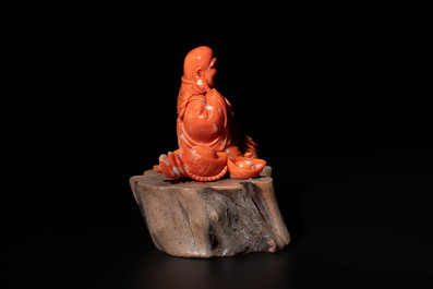 A Chinese red coral sculpture of a Milefo Buddha on wooden stand, 19/20th C.