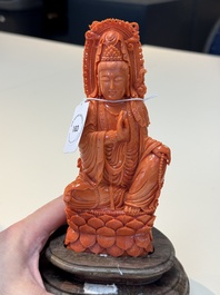 A fine Chinese red coral sculpture of Guanyin seated on a lotus throne on a wooden stand, 19/20th C.