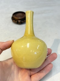 A Chinese copper-red 'mythical beasts' vase and a yellow-glazed bottle vase, with two wooden stands, Kangxi and later