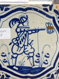 Two blue and white Dutch Delft 'castle' and 'soldier with coloured flame' tiles, 17th C.