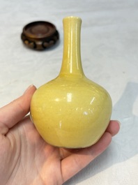 A Chinese copper-red 'mythical beasts' vase and a yellow-glazed bottle vase, with two wooden stands, Kangxi and later
