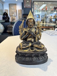 A Tibetan parcel-gilt bronze sculpture of a lama, 20th C.