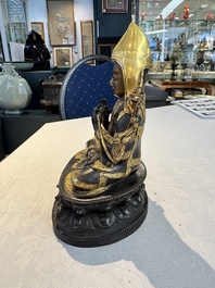 A Tibetan parcel-gilt bronze sculpture of a lama, 20th C.