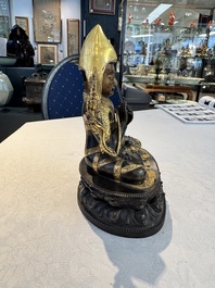 A Tibetan parcel-gilt bronze sculpture of a lama, 20th C.