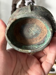 A Chinese archaic bronze food vessel and cover with taotie design, 'zhi 觶', Shang