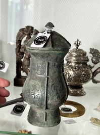 A Chinese archaic bronze food vessel and cover with taotie design, 'zhi 觶', Shang