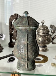 A Chinese archaic bronze food vessel and cover with taotie design, 'zhi 觶', Shang