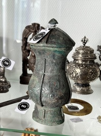 A Chinese archaic bronze food vessel and cover with taotie design, 'zhi 觶', Shang