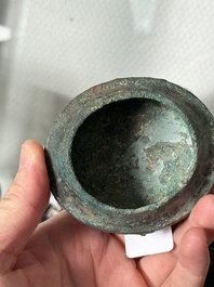 A Chinese archaic bronze food vessel and cover with taotie design, 'zhi 觶', Shang