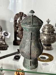 A Chinese archaic bronze food vessel and cover with taotie design, 'zhi 觶', Shang