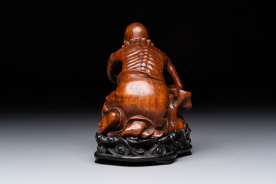 A Chinese fine huanghuali sculpture of a Luohan on a zitan stand, Qianlong mark, 19/20th C.