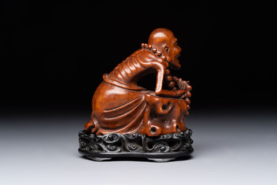 A Chinese fine huanghuali sculpture of a Luohan on a zitan stand, Qianlong mark, 19/20th C.