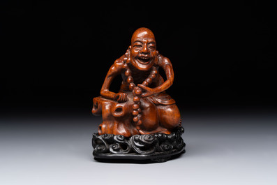 A Chinese fine huanghuali sculpture of a Luohan on a zitan stand, Qianlong mark, 19/20th C.