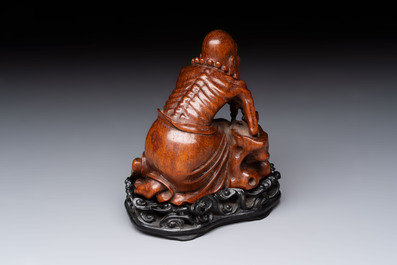 A Chinese fine huanghuali sculpture of a Luohan on a zitan stand, Qianlong mark, 19/20th C.