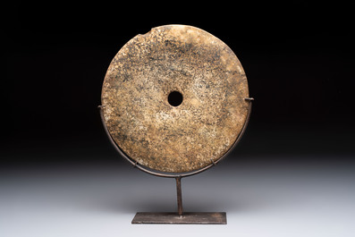 A Chinese archaic calcified jade 'bi' disc on an iron stand, Zhou