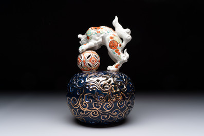 A Japanese Kutani group of a Shishi standing on an openworked brocade ball, 20th C.