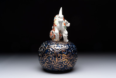A Japanese Kutani group of a Shishi standing on an openworked brocade ball, 20th C.