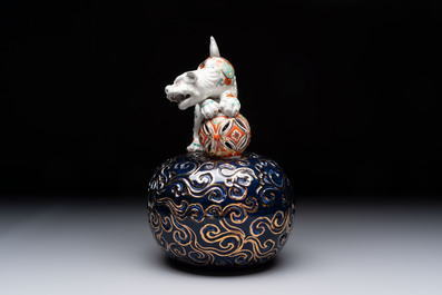 A Japanese Kutani group of a Shishi standing on an openworked brocade ball, 20th C.
