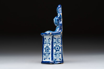 A blue and white Dutch Delft group of a child seated in a high chair, 18th C.