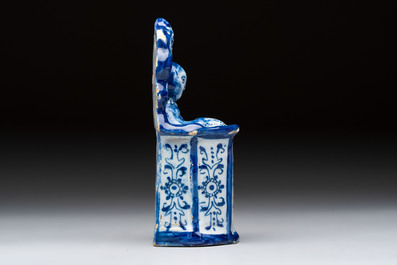 A blue and white Dutch Delft group of a child seated in a high chair, 18th C.