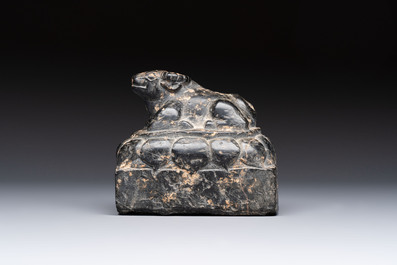 A Chinese carved black stone paper weight in the shape of a reclining buffalo on a lotus throne, Northern and Southern dynasties