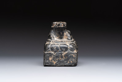 A Chinese carved black stone paper weight in the shape of a reclining buffalo on a lotus throne, Northern and Southern dynasties