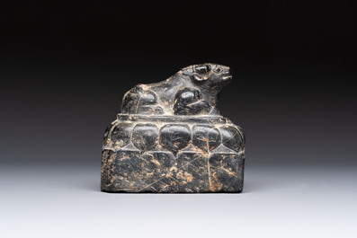 A Chinese carved black stone paper weight in the shape of a reclining buffalo on a lotus throne, Northern and Southern dynasties