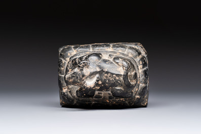 A Chinese carved black stone paper weight in the shape of a reclining buffalo on a lotus throne, Northern and Southern dynasties