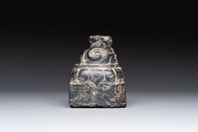 A Chinese carved black stone paper weight in the shape of a reclining buffalo on a lotus throne, Northern and Southern dynasties