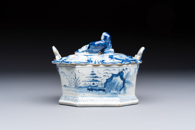A blue and white Dutch Delft chinoiserie butter tub with a reclining figure finial, 18th C.