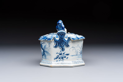 A blue and white Dutch Delft chinoiserie butter tub with a reclining figure finial, 18th C.
