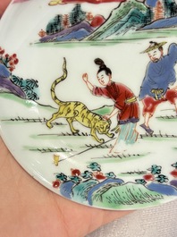 A pair of Chinese famille rose 'Taming the Tiger' saucers, Yongzheng
