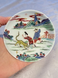 A pair of Chinese famille rose 'Taming the Tiger' saucers, Yongzheng