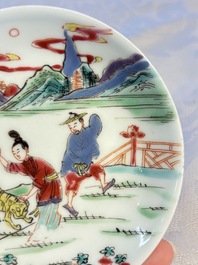 A pair of Chinese famille rose 'Taming the Tiger' saucers, Yongzheng