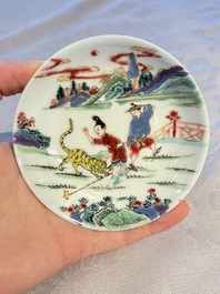 A pair of Chinese famille rose 'Taming the Tiger' saucers, Yongzheng