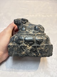 A Chinese carved black stone paper weight in the shape of a reclining buffalo on a lotus throne, Northern and Southern dynasties
