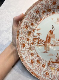 A pair of Chinese iron-red and gilt-decorated 'Elegant Beauties in a Garden' dishes, Kangxi