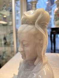 An exceptional and large Chinese carved pale lavender jadeite Guanyin on a wooden stand, Republic