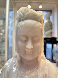 An exceptional and large Chinese carved pale lavender jadeite Guanyin on a wooden stand, Republic