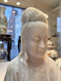 An exceptional and large Chinese carved pale lavender jadeite Guanyin on a wooden stand, Republic