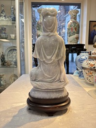 An exceptional and large Chinese carved pale lavender jadeite Guanyin on a wooden stand, Republic