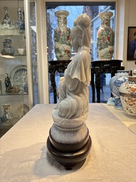 An exceptional and large Chinese carved pale lavender jadeite Guanyin on a wooden stand, Republic