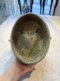 A Chinese archaic bronze wine vessel and cover with Taotie design, You 卣, late Shang