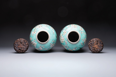 A pair of fine Chinese famille verte turquoise-ground 'Magpie and Prunus' jars with reticulated wooden covers, 19th C.