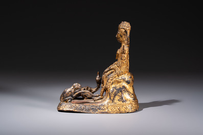A Thai gilt-bronze figure of a seated deity with attendant animals, 19th C.
