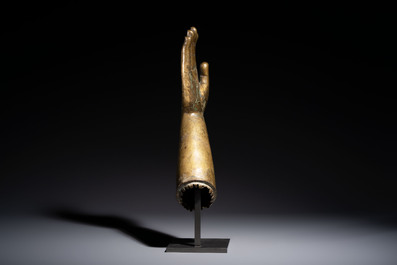 A rare and large Tibetan bronze forearm of a Buddhist figure with a chakra design, on a later metal stand, Qing