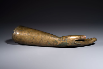 A rare and large Tibetan bronze forearm of a Buddhist figure with a chakra design, on a later metal stand, Qing