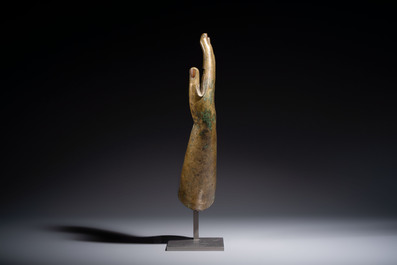 A rare and large Tibetan bronze forearm of a Buddhist figure with a chakra design, on a later metal stand, Qing