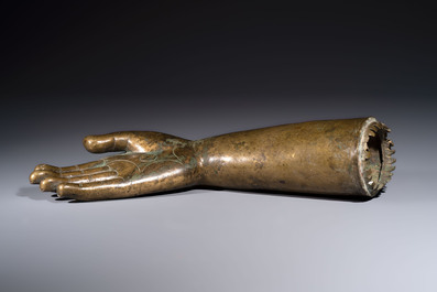 A rare and large Tibetan bronze forearm of a Buddhist figure with a chakra design, on a later metal stand, Qing