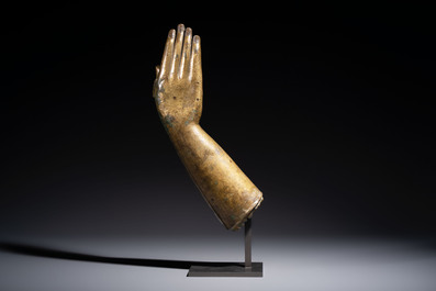 A rare and large Tibetan bronze forearm of a Buddhist figure with a chakra design, on a later metal stand, Qing